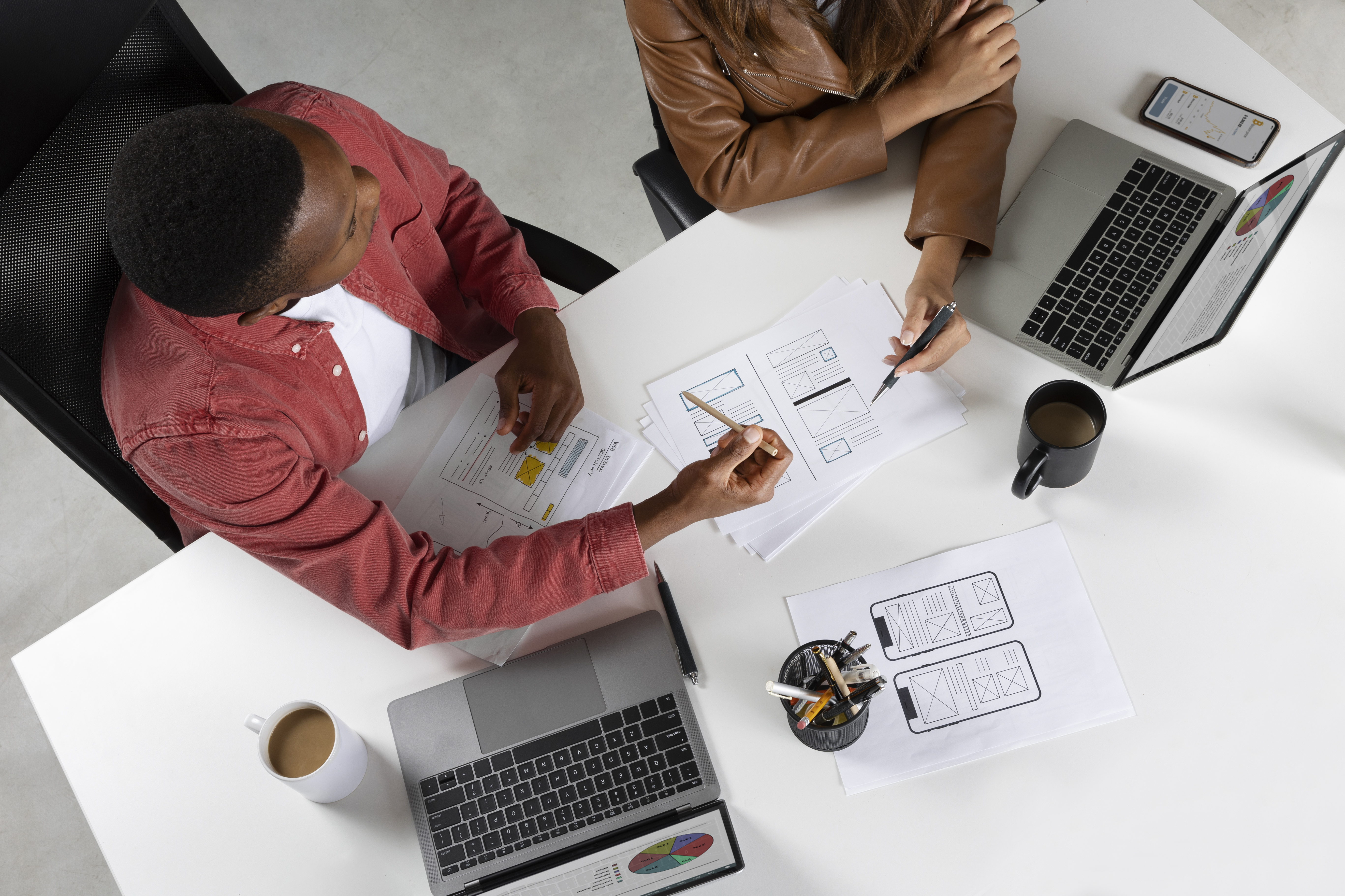 Top view of professionals collaborating on laptops